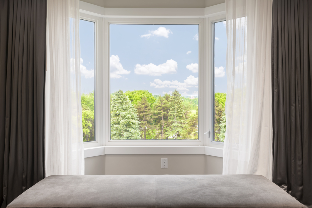 Bay,window,with,drapes,,curtains,and,view,of,trees,under
